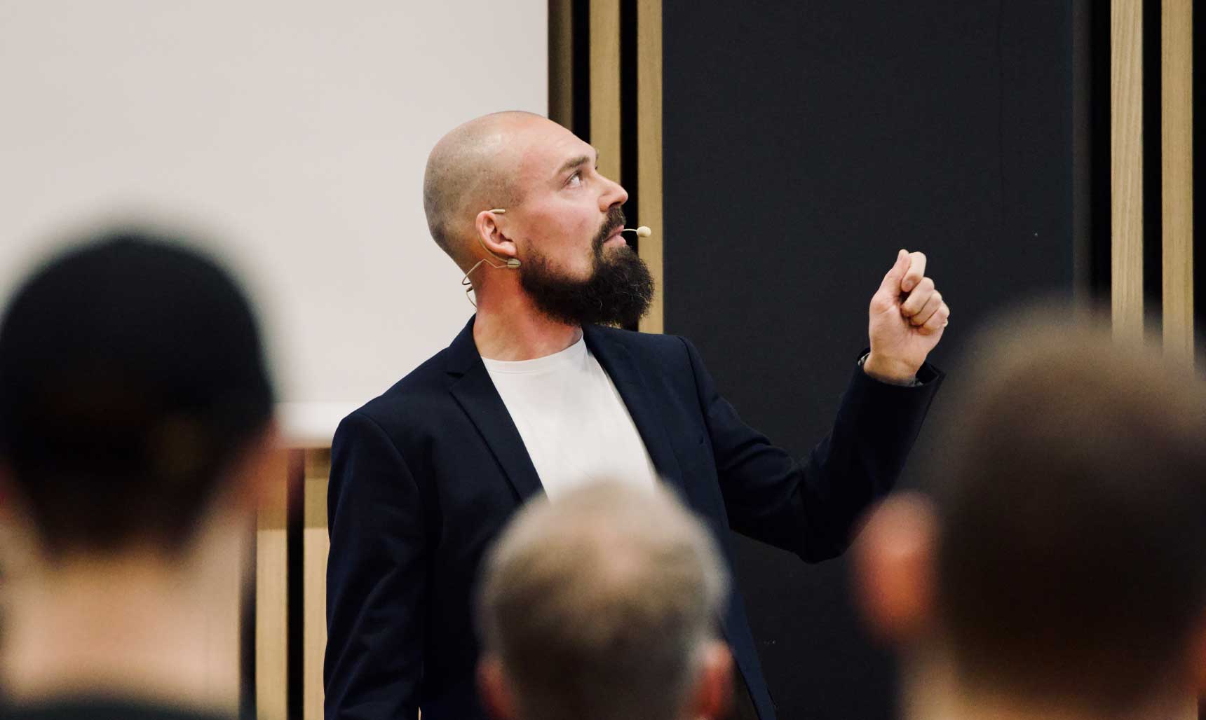 Rasmus Kragh holder foredrag på en scene med publikum i forgrunden