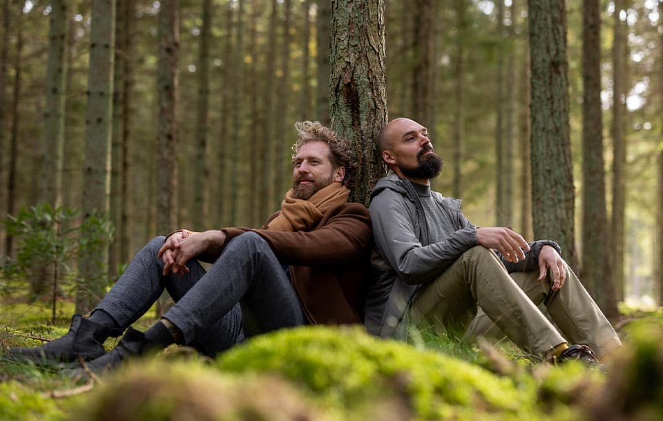 Rasmus Kragh og en klient sidder ryg mod ryg op ad et træ i skoven